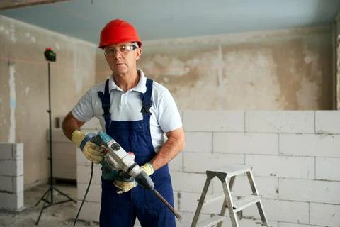 Professional construction worker in uniform standing with rotary hammer drill Stock Photos