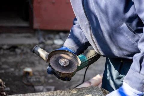 A professional construction worker uses a handheld angle grinder with a sha.. Stock Photos