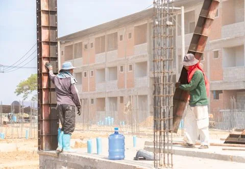 Professional construction workers installing heavy steel column formwork fo.. Фото