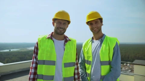 Professional construction workers in safety helmets and jackets smiling camera Видео 117217573