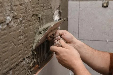 Professional constructor applying glue before laying ceramic tiles on the wall 写真素材