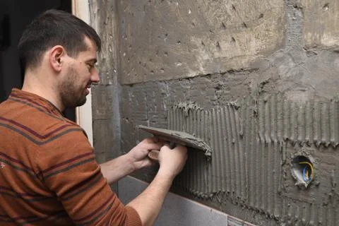 Professional constructor applying glue before laying ceramic tiles on the wall Stock-Fotos