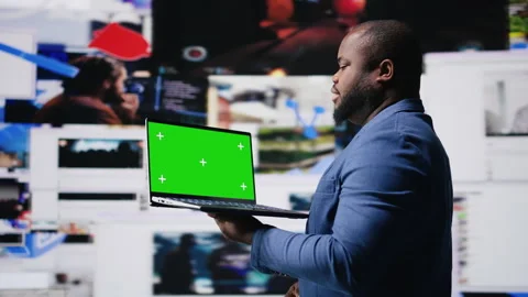 Professional content creator in a multitasking space holds green screen Stock Footage 312414161