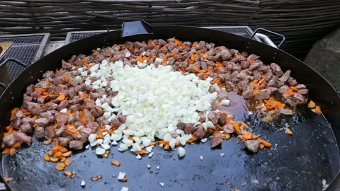 Professional cook stirring and mixing vegetables and pork meat in big frying pan Stock Footage 132693377