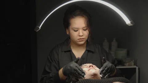 Professional cosmetologist cleaning client face Stock Footage 330525765