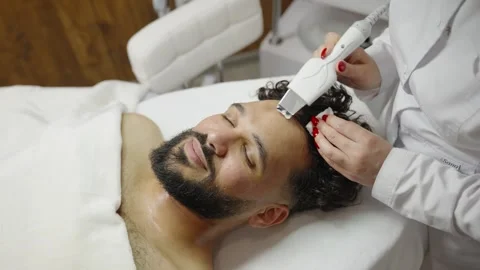Professional cosmetologist doing ultrasonic face cleaning for man Stock Footage 344872848