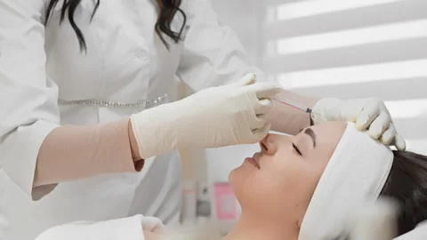 A professional cosmetologist in white gloves performs a facial injection 库存影片 341037031