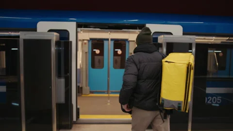 Professional courier service. Deliveryman with a backpack enters a subway car Stock Footage 236089129