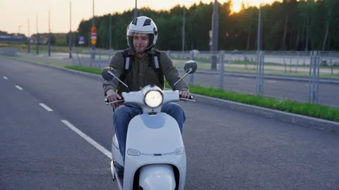 A professional courier with a yellow backpack rides a scooter around the city Stock Footage 233977212