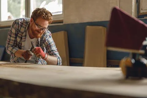 Professional craftsman working with chisel while cutting wooden plank in Stock Photos