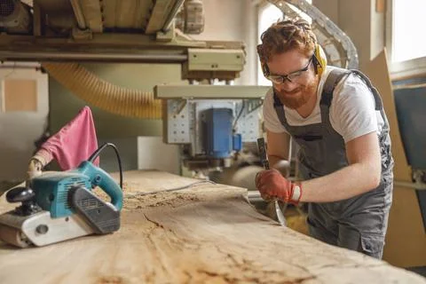 Professional craftsman working with chisel while cutting wooden plank in Stock Photos