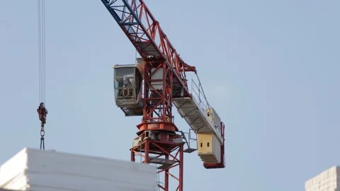 Professional crane operator working in cab of crane on background blue sky Stock Footage 101838140