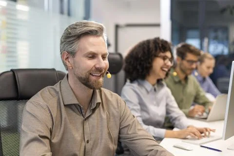 Professional customer support agent man in assisting customers at call center Foto stock