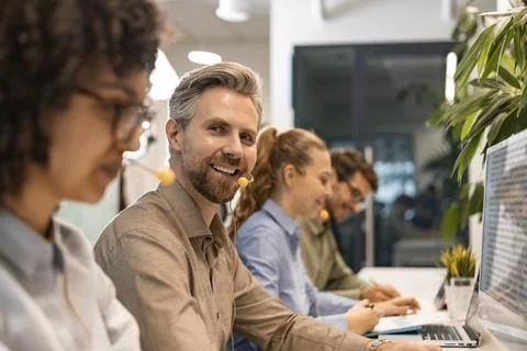 Professional customer support agent man in assisting customers at call center Stock Photos