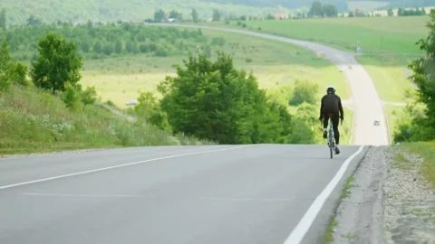 A professional cyclist rides on an empty highway going down a hill, beautiful Stock Footage 147997251