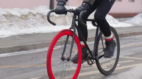 Professional cyclist rides fixed gear bike with red front wheel on an empty road Stock Footage 163138528
