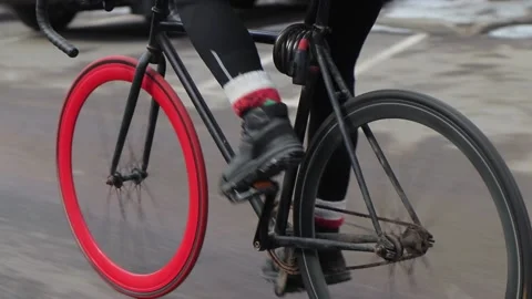 Professional cyclist rides fixed gear bike with red front wheel on an empty road 動画素材 163138532
