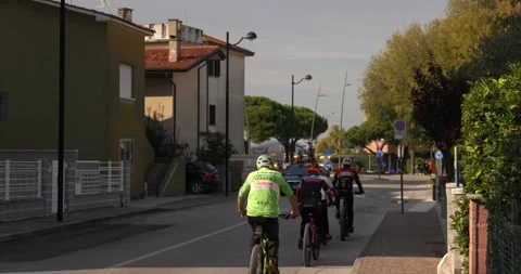 Professional cyclists passing by on a main road next to an italian flag waving Stock Footage 150391629