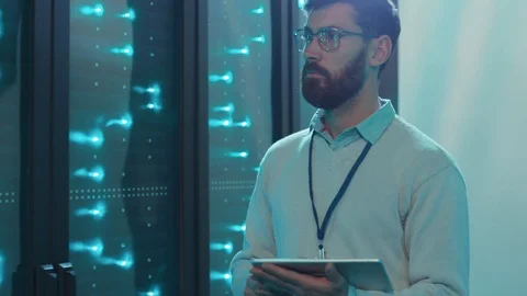 Professional data center specialist walking at row of operational rack servers Stock Footage 119233585