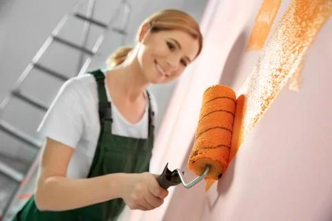 Professional decorator painting wall indoors. Home repair service Stock Photos