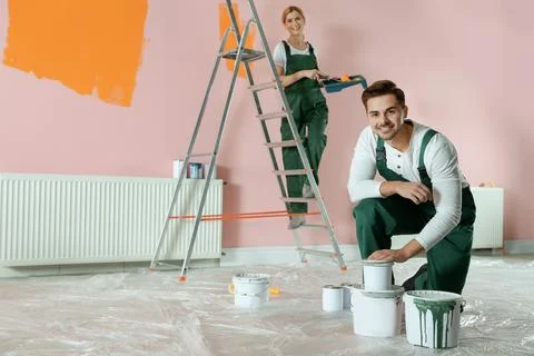 Professional decorators painting wall indoors. Home repair service Stock Photos