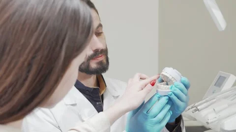 Professional dentist demonstrating teeth mold to attentive patient Stock Footage 311228723