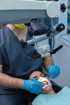 Professional Dentist Using a Microscope While Performing Oral Treatment on Stock Photos
