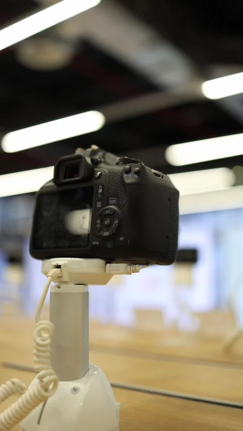 Professional digital camera displayed on security stand in electronics store Stock Footage 345357363