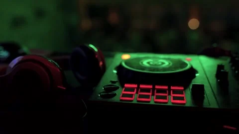 Professional DJ controller and headphones with neon lighting in a dark club Видео 325802224