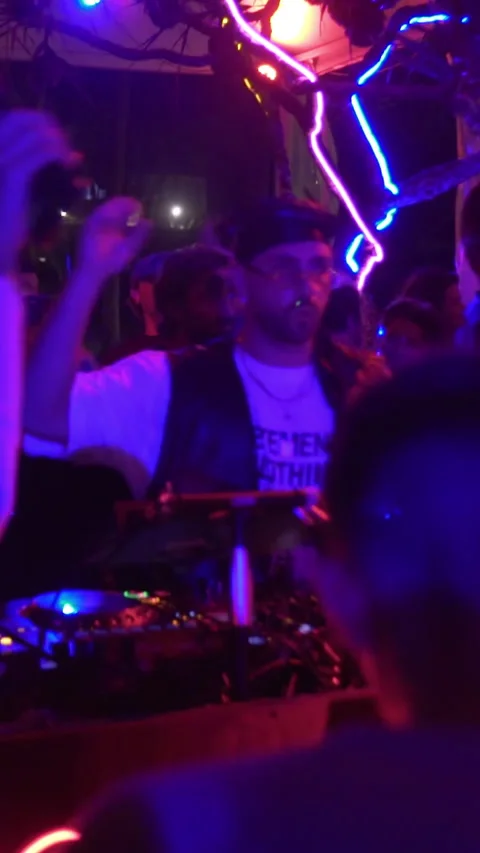 Professional DJ Performing Live at Neon-Lit Beach Club Night Party Stock Footage 337902900
