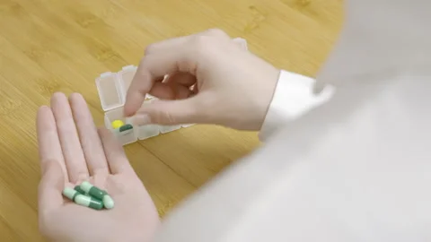 Professional doctor or pharmacist preparing arrange medication dispenser for Vídeos de archivo 332947741