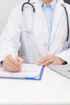 Professional doctor wearing lab coat using laptop and taking report notes o.. Stock Photos