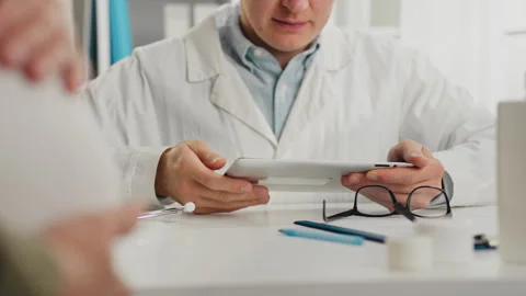 A professional doctor, in a white coat, is working decisively with a tablet Stock Footage 323706680