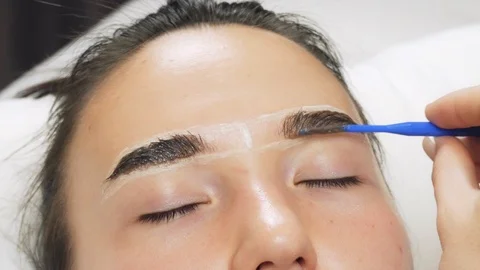 A professional does dyeing eyebrows with dyes, tinting. Vídeo Stock 121737376