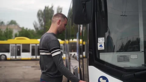 Professional driver comes up to trolleybus and opens door to enter it. Young man Stock Footage 255272756