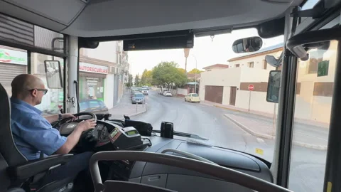 Professional driver maneuvering a bus through a narrow European city street Stock Footage 337068822