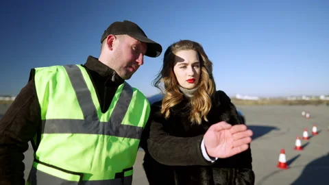 Professional driving instructor gesturing explaining road cone passing to Stock Footage 148747210