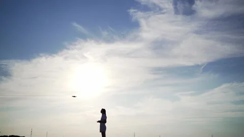 A professional drone pilot controls it against the sunset sky. Copter operator Stock Footage 136659162