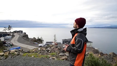 A professional drone pilot flying a drone near the ocean. HD 24FPS Stock Footage 124394990
