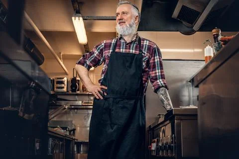 Professional elderly butcher inside modern kitchen of restaurant Stock Photos