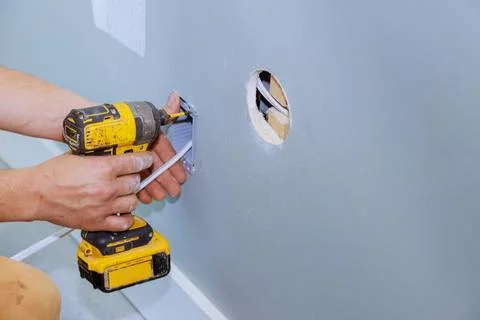 Professional electrician installing an electric socket in wall of a renovation Stock Photos