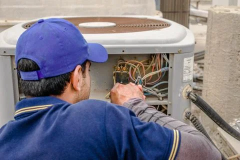 A professional electrician man is fixing the heavy air conditioner Stock Photos