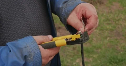 Professional electrician stripping insulation from a black electrical cable with Stock Footage 334574171