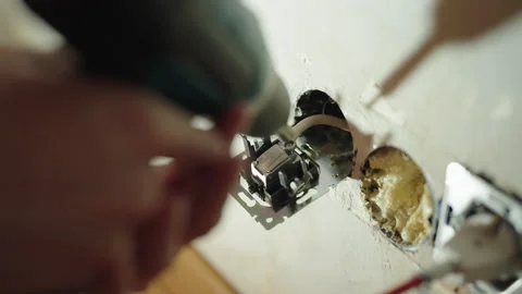 Professional electrician using cordless screwdriver to disassemble electrical Stock Footage 305999608