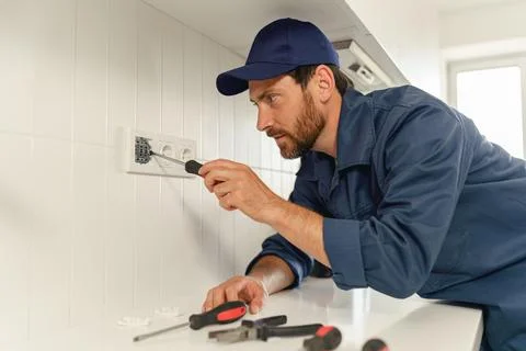 Professional electrician using screwdriver while installing new electrical Stock Photos
