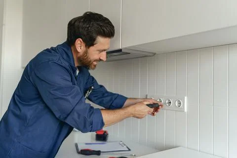 Professional electrician using screwdriver while installing new electrical Stock Photos