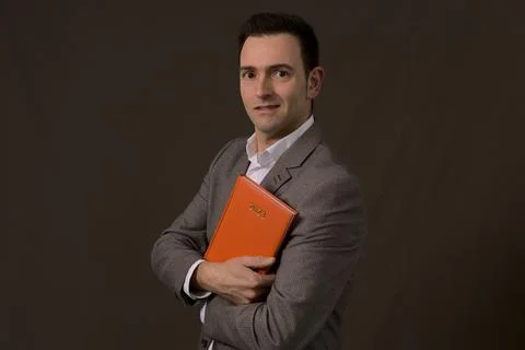 Professional Elegant formal self employed smiles and holds a 2023 orange agenda Stock Photos