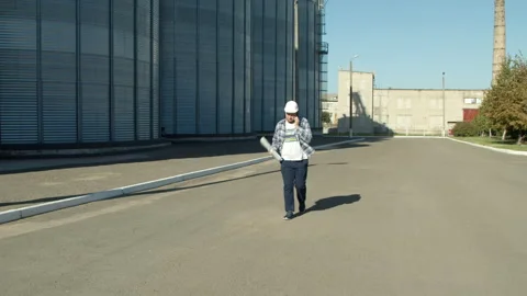 Professional engineer with blueprints inspecting agricultural silos Stock Footage 142603512