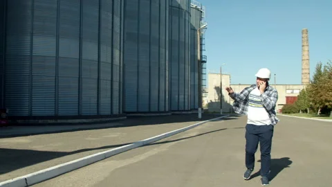 Professional engineer with blueprints inspecting agricultural silos Stock Footage 142604495