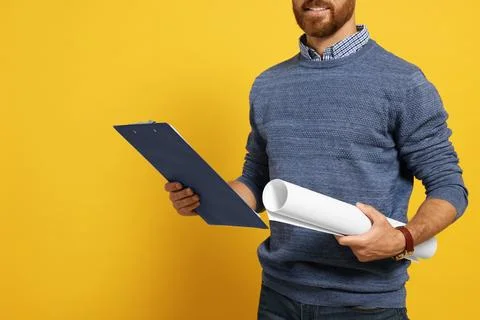 Professional engineer with clipboard and draft on yellow background, closeup Stock Photos